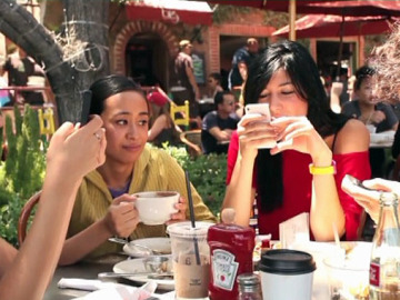 Tres personas consultan su teléfono móvil durante una comida Tres personas consultan su teléfono móvil durante una comida