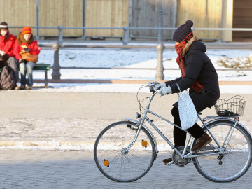 Una ciclista en bici con mucho fr&iacute;o