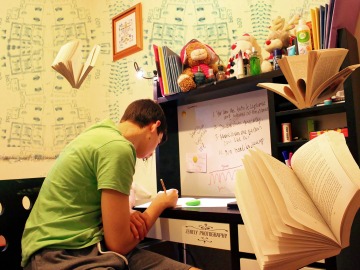 Un chico estudiando en su habitaci&oacute;n