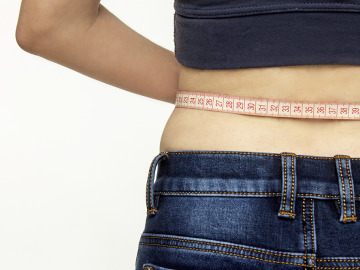 Una mujer mide su cintura